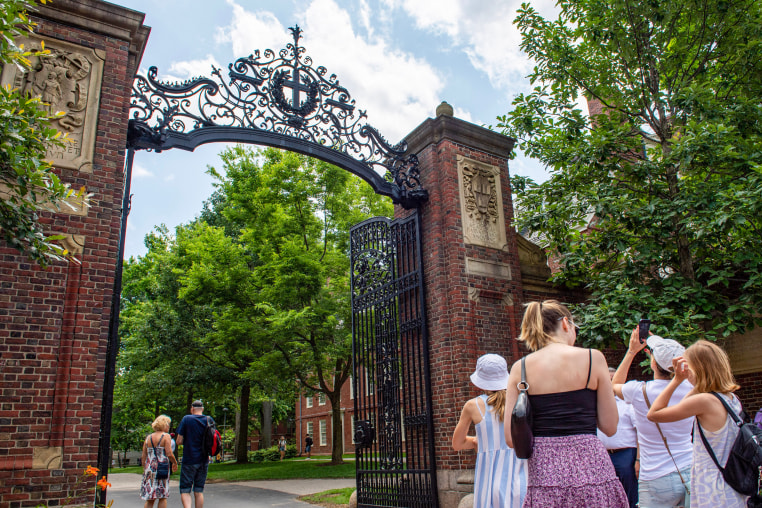People take photos by the entrance to Harvard Yard.